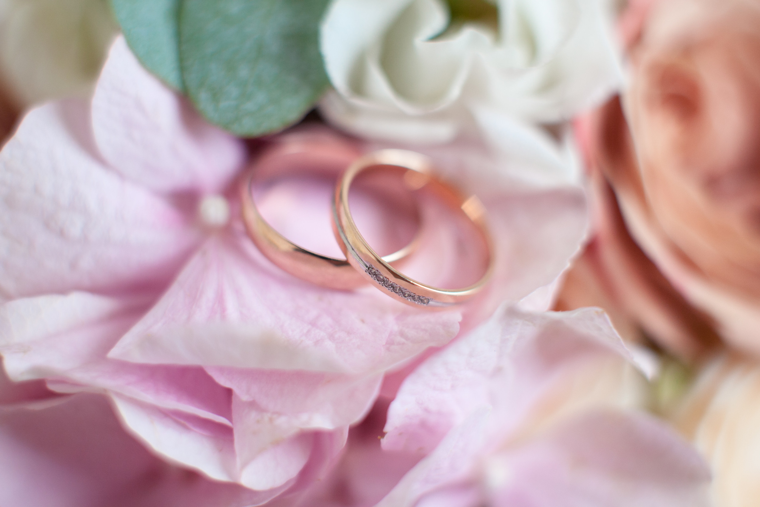 Gold wedding rings on a wedding bouquet of pink roses